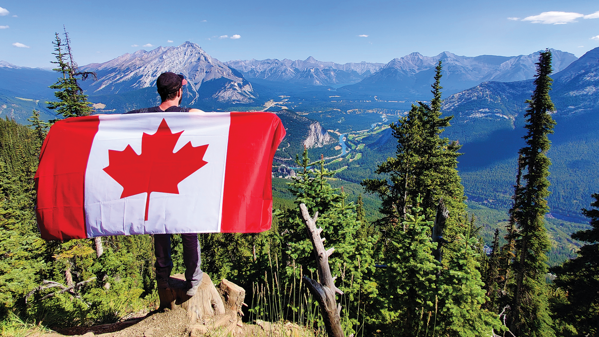 Male holding Canada flag on top of mountain
