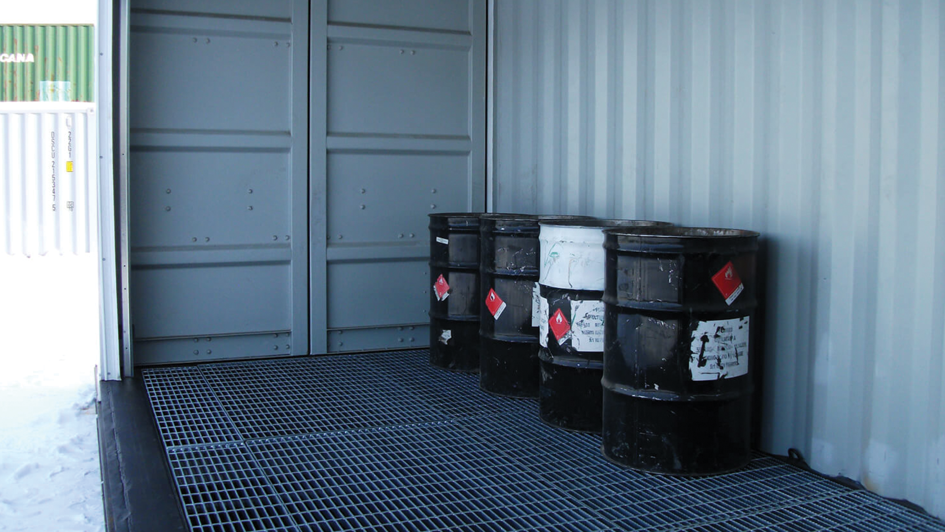 Interior of container with oil barrels sitting on top of metal grade