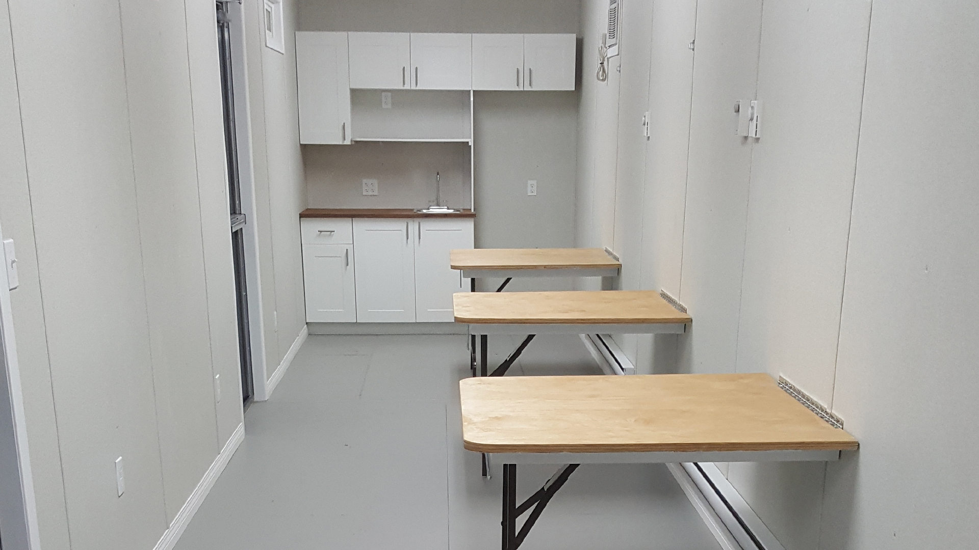 Lunch room with three tables and sink inside of container