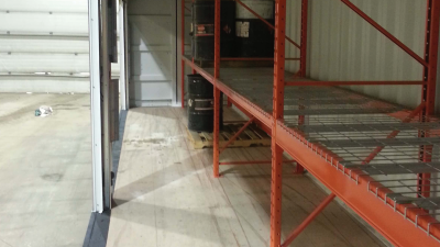 Inside of container with bay doors opened on the left and orange shelves on the right