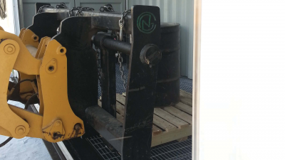 Fork lift moving pallet with oil barrels on it into a container