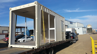 Exterior of smaller container with three side open on top of trailer