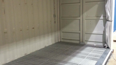 Inside of container with large bay door open and metal grading on floor
