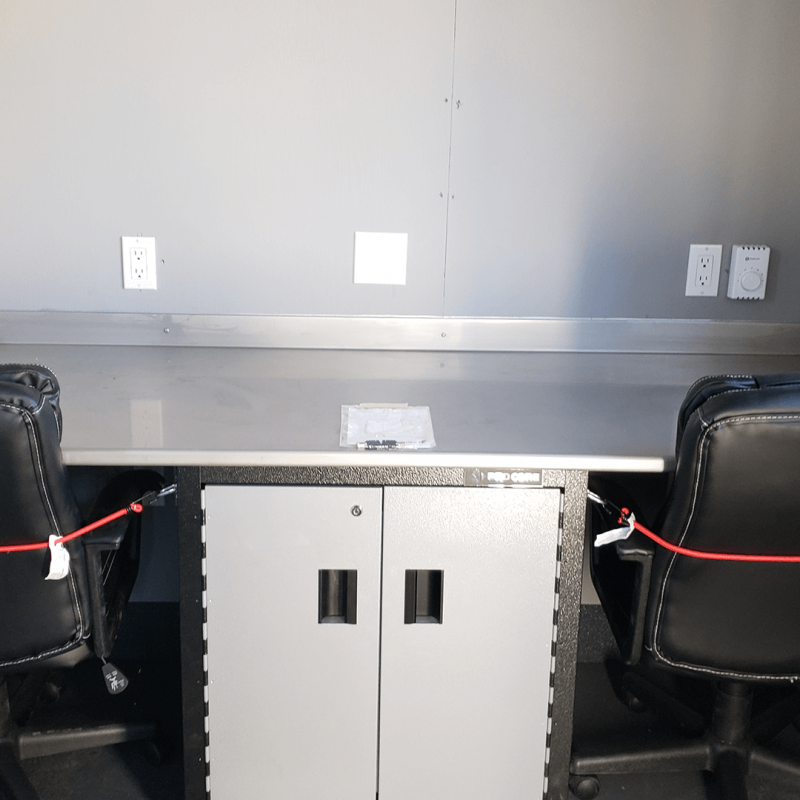 Two office chairs and desks inside of office container