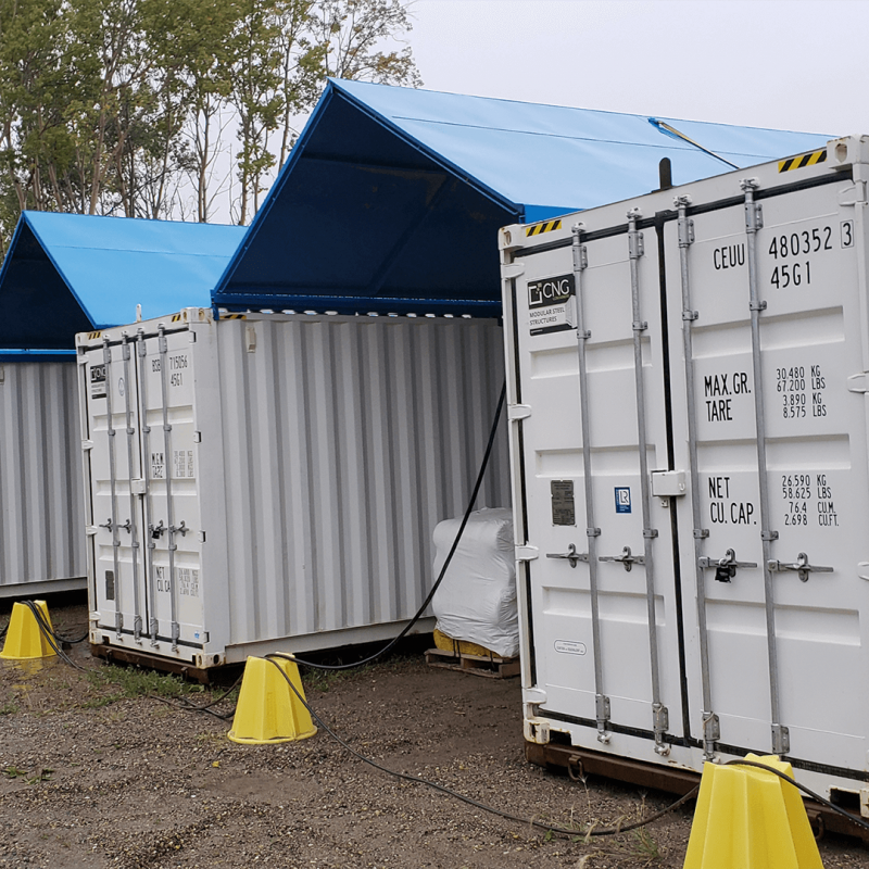 Row of white containers with blue tent in between them