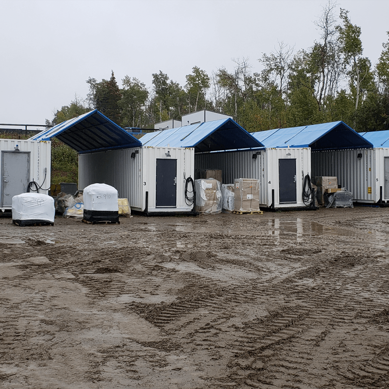 Row of white containers in a muddy yard