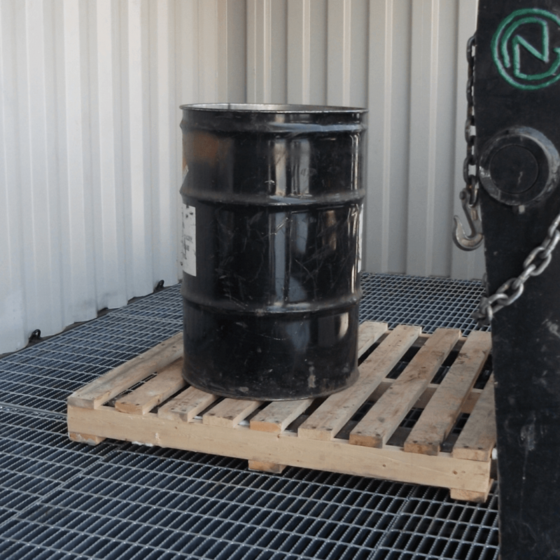 Forklift placing a pallet with a single oil barrel inside of spill container